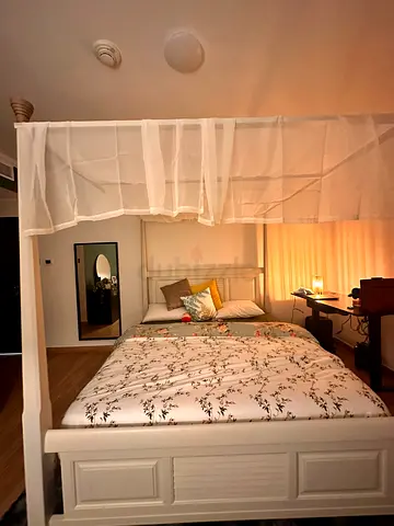 White wooden four-poster double bed with sheer curtains