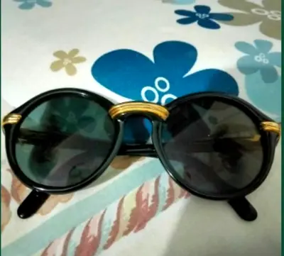 Black round sunglasses with gold bridge and accents