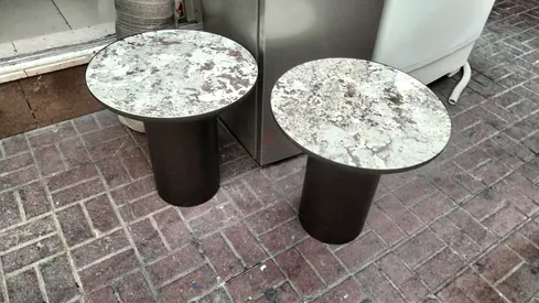 Pair of round marble-top side tables with black cylindrical bases
