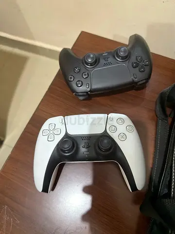 Two PlayStation 5 DualSense controllers - black and white, used