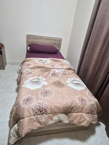 Single wooden bed with mattress and bedding