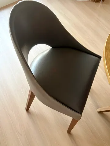 Modern curved dining chair with leather upholstery and wooden legs