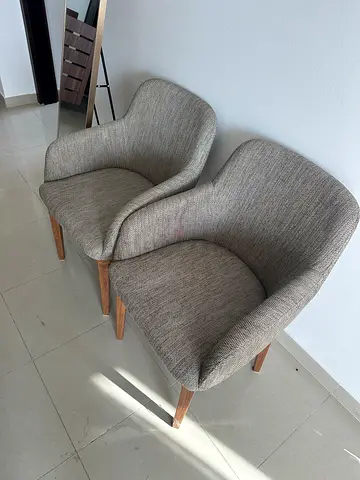 Pair of light grey upholstered lounge chairs with wooden legs