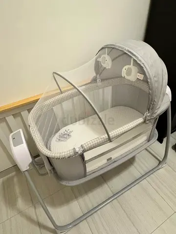 Light grey bedside bassinet with canopy and toy mobiles