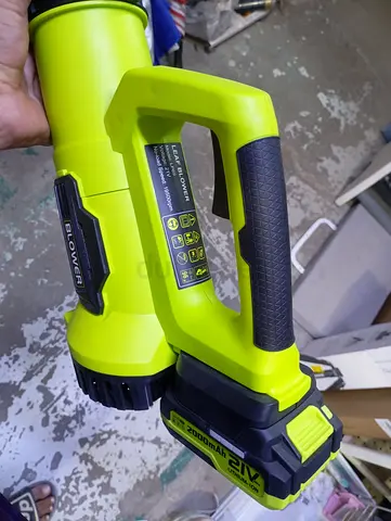 Lime green and black handheld cordless electric leaf blower powered by a 21V battery.