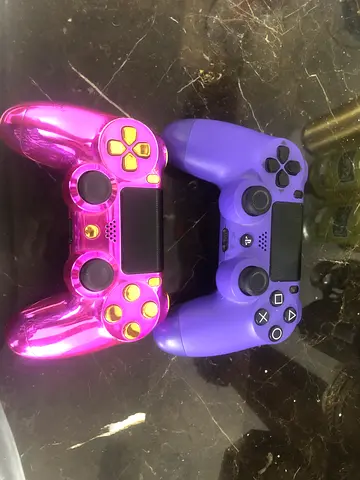 Two Sony DualShock 4 controllers - purple and metallic pink.