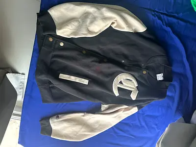 A luxurious black and beige jacket from a world-renowned brand, designed for men and teenagers.