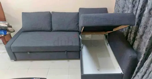 L-shaped grey fabric sofa bed with storage and pull-out bed
