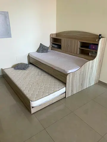 Wooden bunk-style bed with storage headboard and trundle mattress
