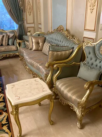 Classic gold-accented ornate sofa set with matching armchairs and tables as well as curtains