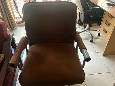 Brown upholstered armchair with metal frame and padded arms - used