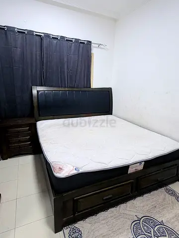 Dark wooden storage bed with built-in base drawers and a quilted white mattress.
