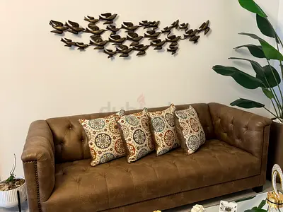 Brown tufted leather-style 3-seater sofa with cushions