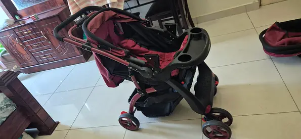 Lightly used maroon baby stroller with detachable bassinet and storage basket