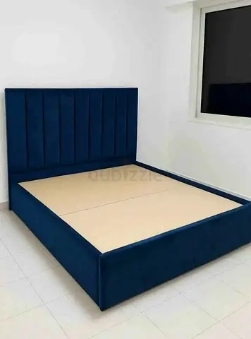 Blue upholstered queen bed frame with tall panelled headboard