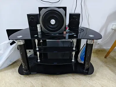 Speakers and subwoofers along with Black glass TV stand with shelves