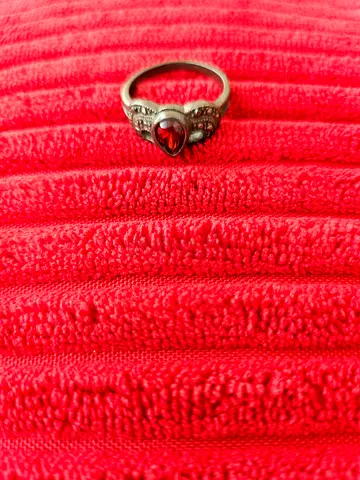 Silver ring with red heart-shaped gemstone and small clear stones