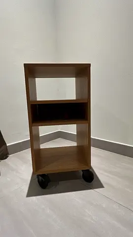 Small mobile wooden storage unit with shelves on wheels