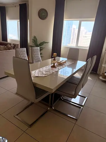 Modern white dining table with 6 upholstered chairs.