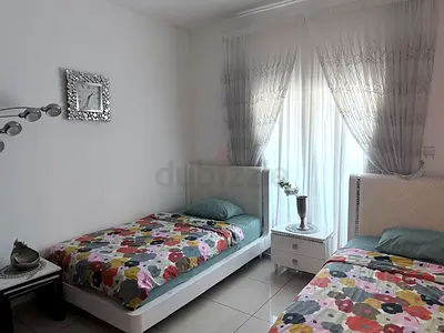 Pair of white single beds with bedside table, watch, side tables, curtains, accessories