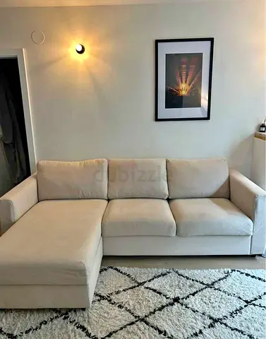 Beige L-shaped sofa bed with chaise lounge - good condition
