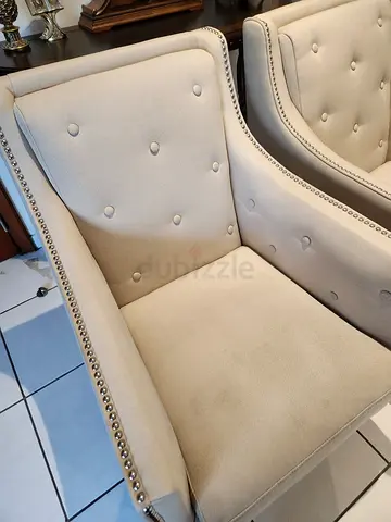 Pair of beige upholstered accent chairs with button tufting and nailhead trim