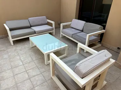 Outdoor glass-top coffee table with white frame, two sofas and one chair