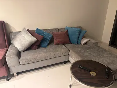 L-shaped grey fabric corner sofa with chaise and cushions