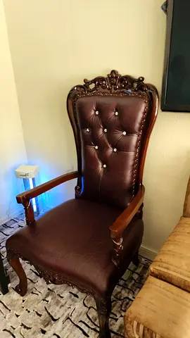Antique-style brown leather armchair with carved wooden frame