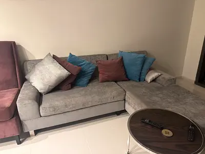 L-shaped grey fabric corner sofa with chaise and cushions