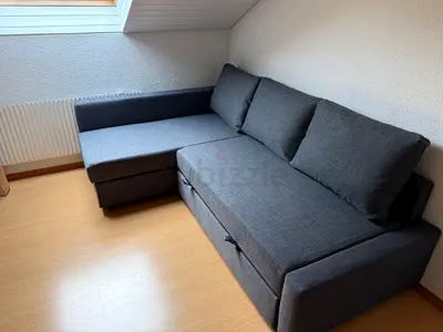 Dark grey L-shaped sofa bed with storage — good condition