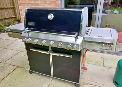 Large stainless steel gas BBQ grill with side burners and storage cabinet