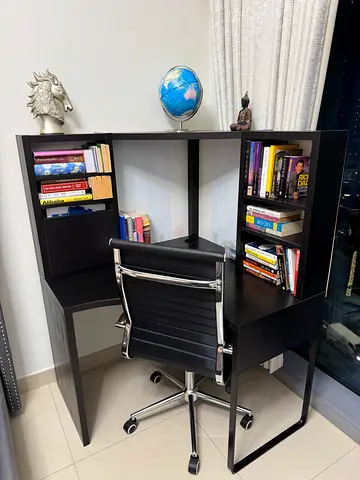 Compact black study desk with built-in bookshelves and swivel chair