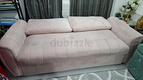 Light pink upholstered three-seater sofa bed in good condition