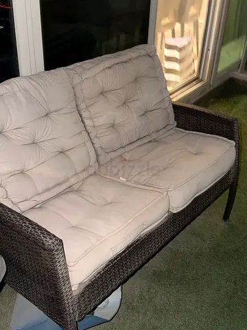 Two-seater outdoor rattan sofa with beige cushions