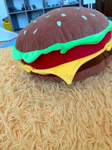 It is a realistic burger with toppings in it, stuffed animal pillow