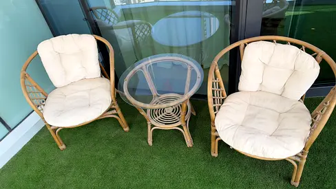 Rattan patio set — 2 cushioned chairs + glass-top side table
