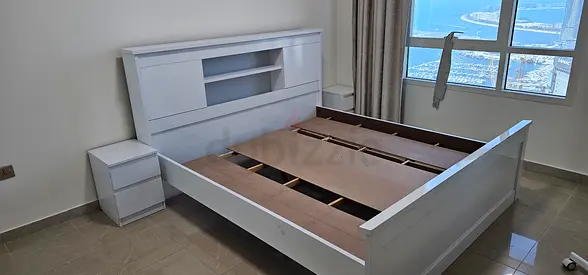 White wooden king-size bed frame with built-in headboard storage and two bedside tables