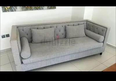 Grey tufted three-seater sofa with bolster cushions. 210 cm x 60 cm
