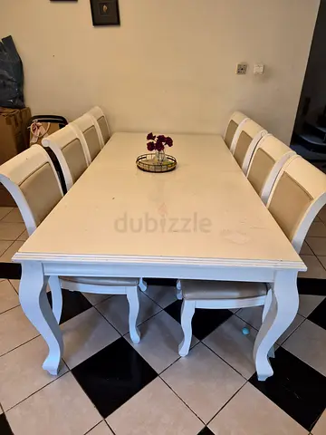 White wooden dining table with 8 upholstered chairs with normal wear and tead - good condition