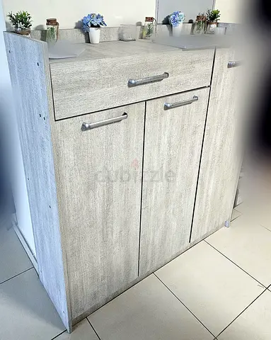 Light wood 3-door cabinet with top drawer — compact storage unit.