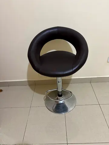 Round height-adjustable bar stool with brown faux leather seat