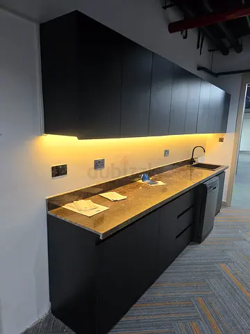 Modern black wall-mounted storage cabinets with countertop and under-cabinet lighting