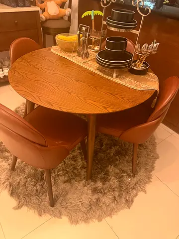 Wooden oval dining table with 4 leather chairs and shaggy round rug