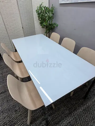 White glass-top dining table with 6 beige modern chairs