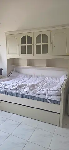 White wooden bed frame with overhead cabinet and storage