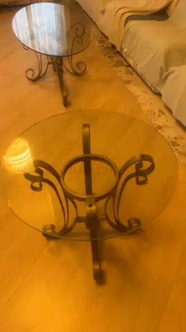 Pair of round glass-top side tables with metal scrollwork bases