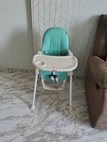 Mint green baby high chair with tray and safety straps