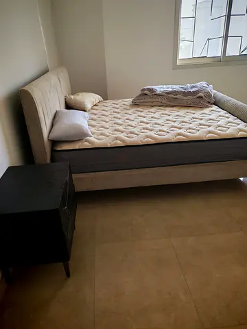 Beige upholstered double bed with mattress and bedside table