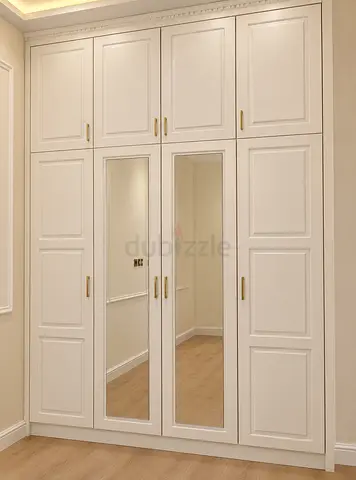 Large built-in white mirrored wardrobe with storage cabinets